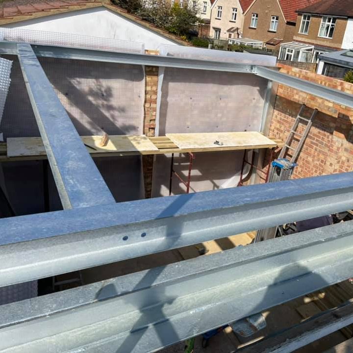 Construction site showing a steel framework with scaffolding and walls under construction.