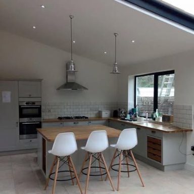 Modern kitchen with a large island, bar stools, and natural light from windows.