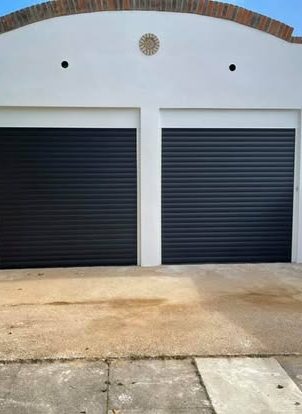 Two closed roller garage doors on a concrete driveway.