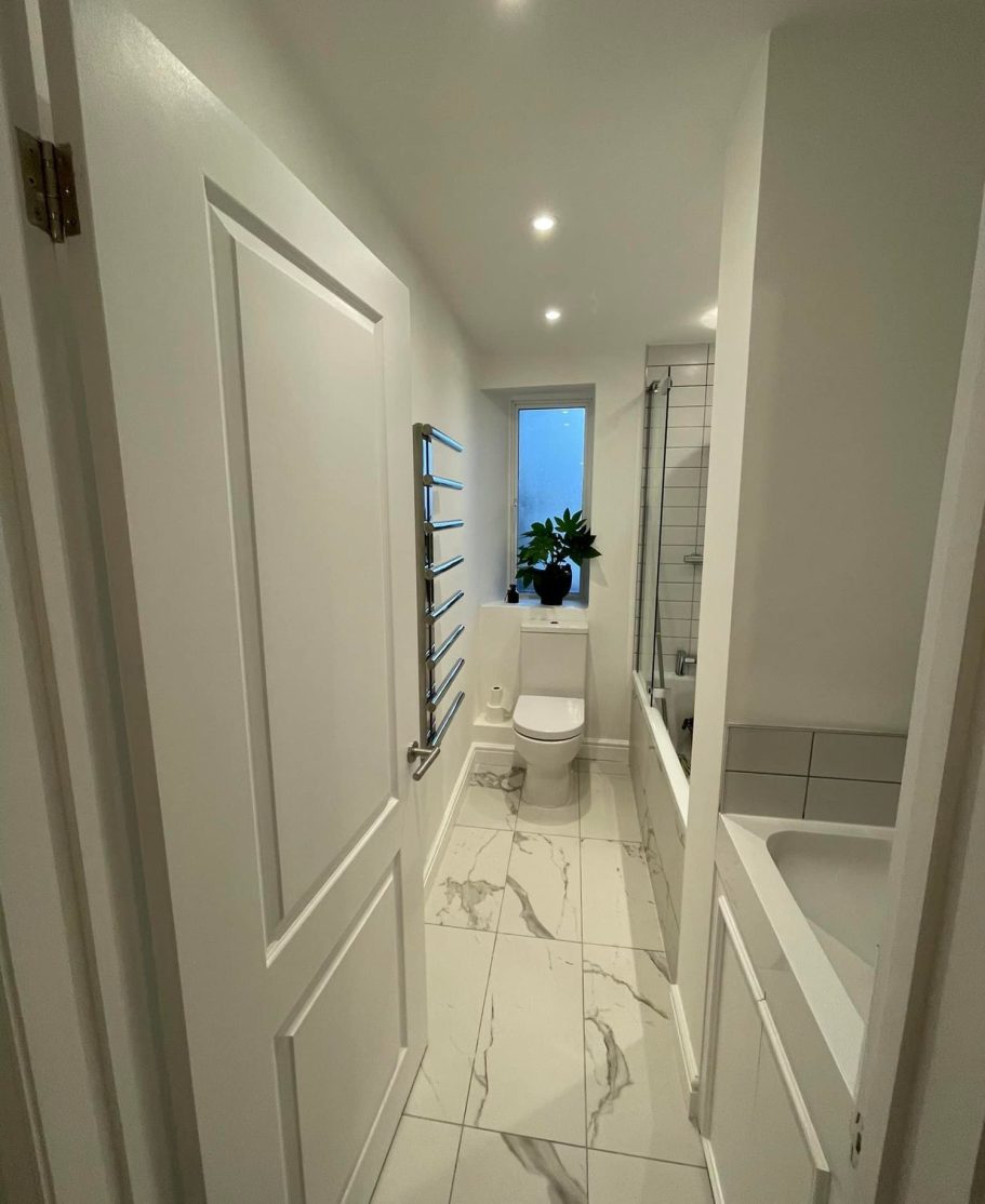 New bathroom with a toilet and large window, featuring light tiles.