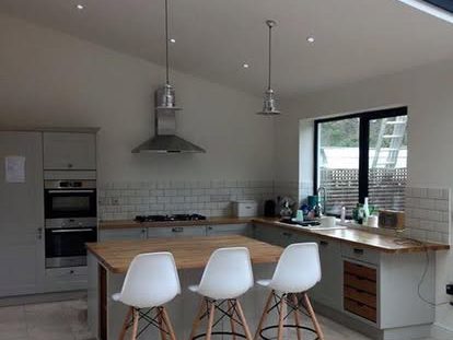 Modern kitchen with pendant lights, an island, and a dining area in the background.
