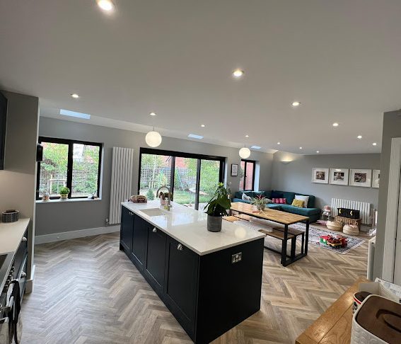 Modern kitchen and living space with an island, dining area, and large windows.