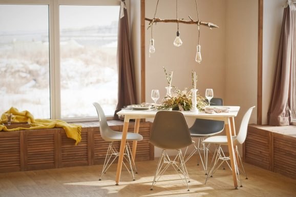 Bright dining area with a wooden table, chairs, and large windows overlooking a snowy landscape.