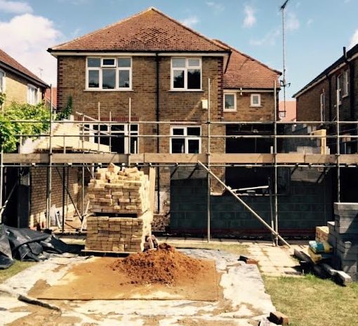 Construction site with a partially built extension on a two-storey house.