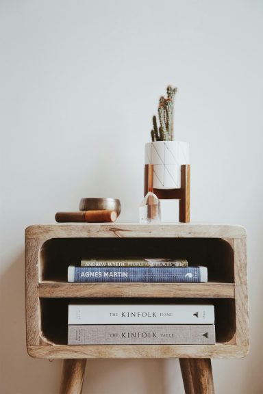 A wooden shelf with books and a small potted plant on top.