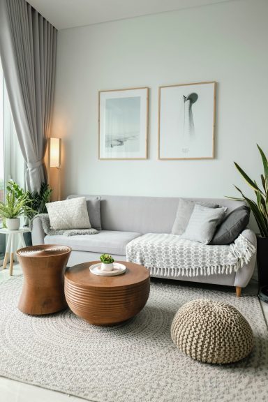 Light and airy living room with a grey sofa, wooden tables, and plants.