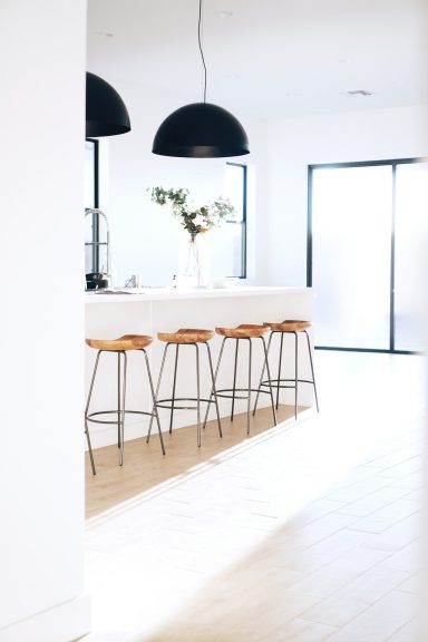 Modern kitchen featuring a sleek bar with wooden stools and large windows.