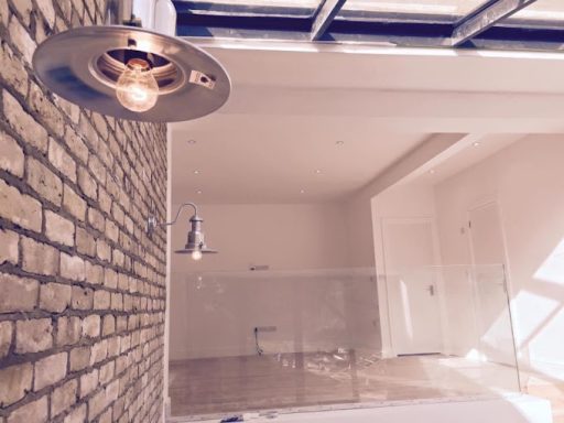 Modern interior with a ceiling light, brick wall, and open space featuring glass railing.