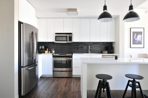 Modern kitchen with sleek white cabinets, black accents, and dark wood flooring.