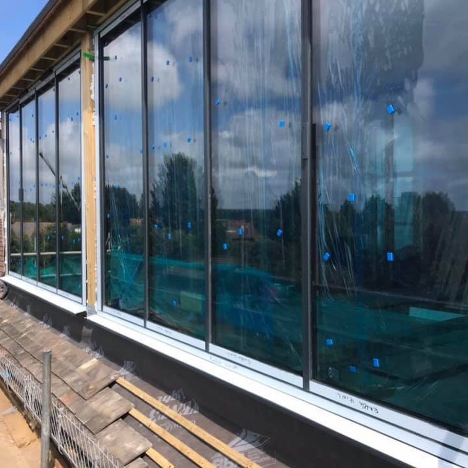 Construction site with large windows and blue markings on the glass.